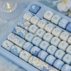 A close-up view of light blue and white PBT keycaps featuring a sea theme used for a mechanical keyboard