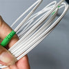 A hand is holding a bundle of white fiber optic cables with green connectors.
