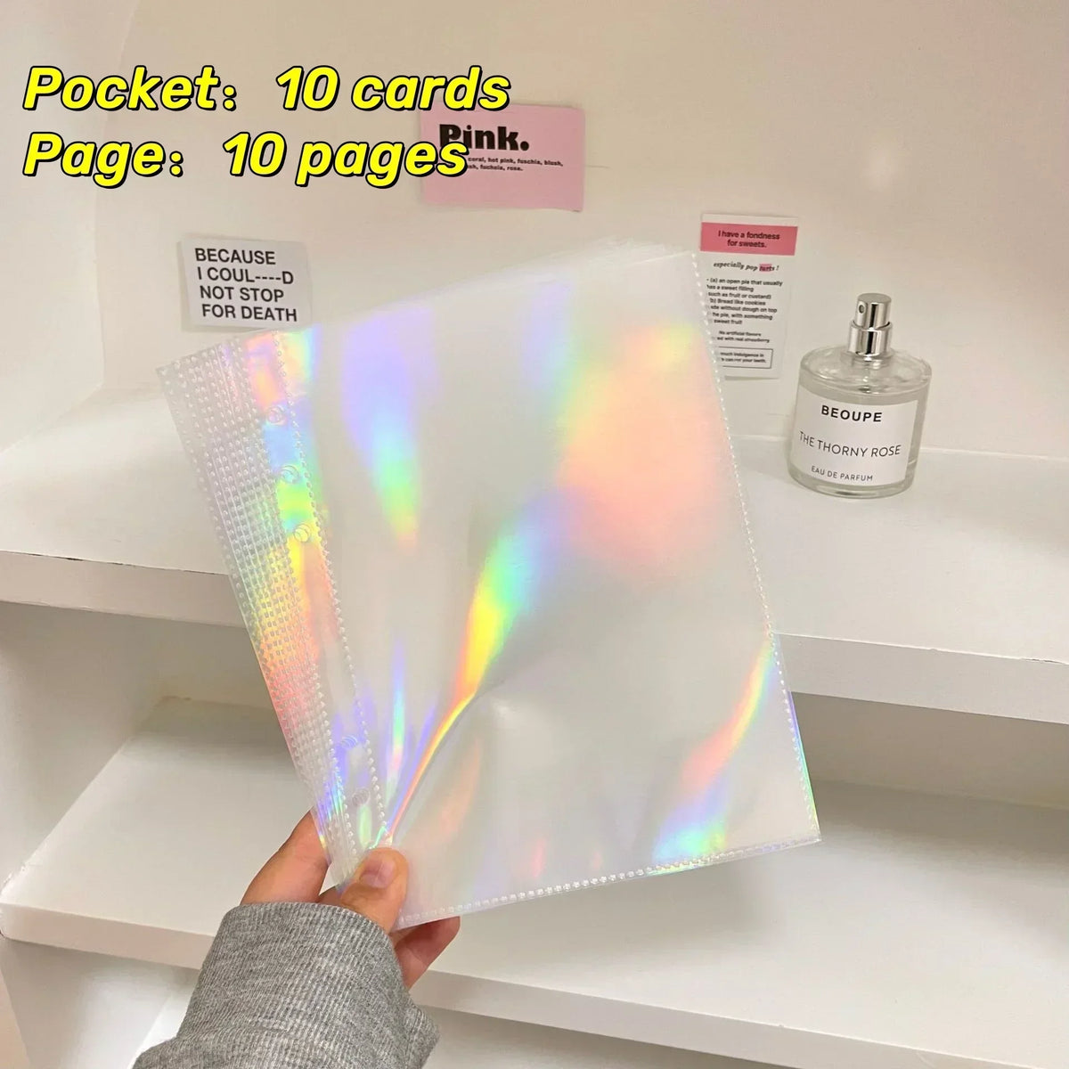 A stack of 10 pink photo sleeves and a bottle of Beoupe perfume are displayed on a white shelf.