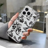A hand holds a clear phone case with a black floral pattern featuring butterflies and vines against a white background.