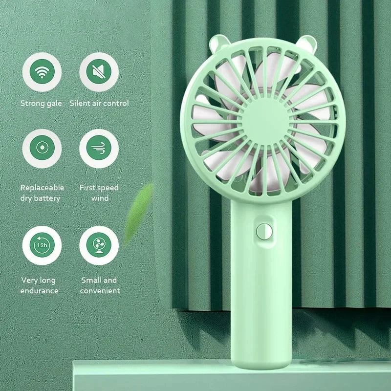 A light green mini handheld fan is shown against a textured green wall, highlighting features like strong gale and long endur