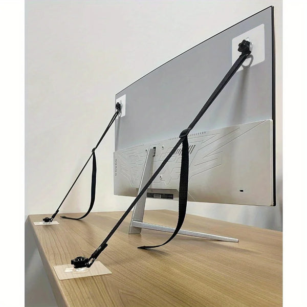 Two adjustable safety straps are shown securing a flat-screen TV to a wooden desk surface.