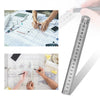 A precision stainless steel measuring ruler set is shown being used to measure and mark on blueprints and technical drawings.