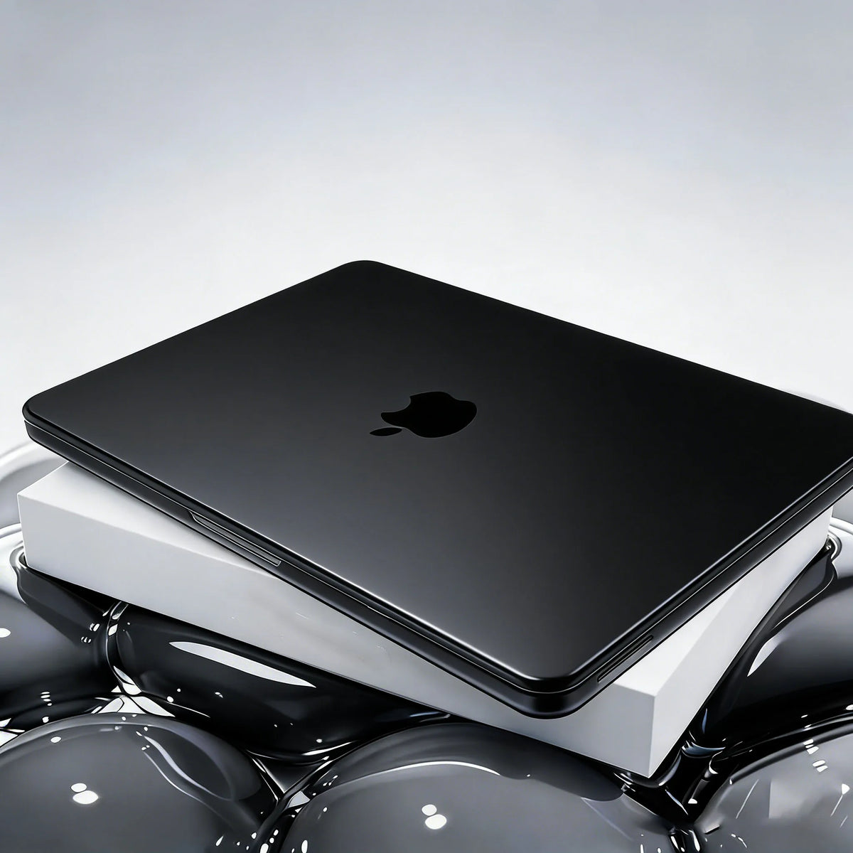 A black Apple laptop is shown inside a white protective case, resting on a reflective surface.