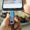 A hand holds a blue SanDisk flash drive, connecting it to a smartphone screen displaying a video player.