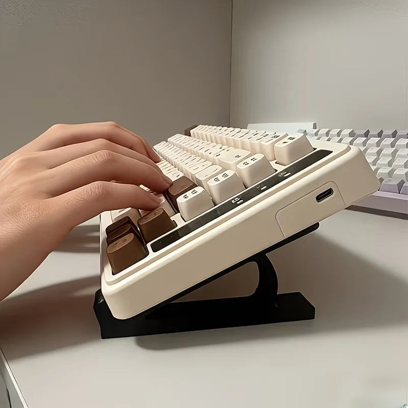 A hand is placing keys onto an adjustable keyboard tray riser set for ergonomic typing.