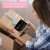 A woman is adding a thank you card to a gift box for business appreciation.