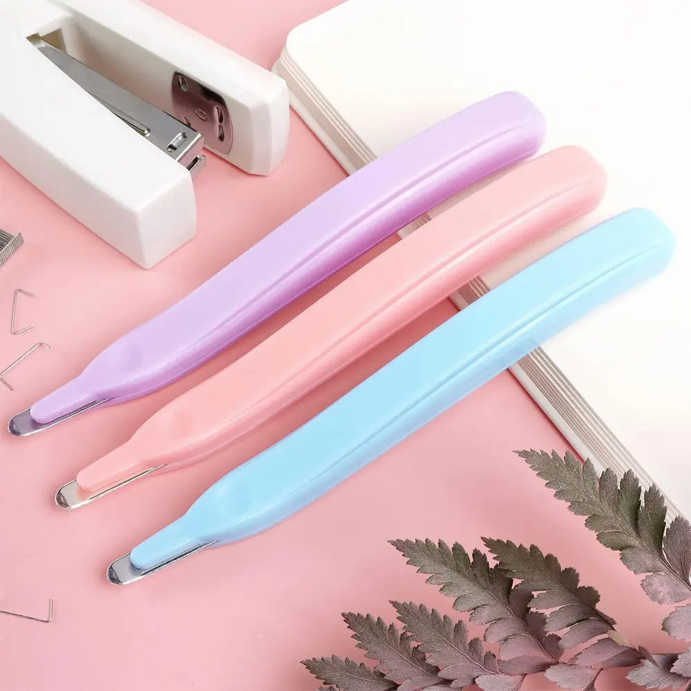 A set of three pastel colored magnetic staple removers displayed on a pink background.