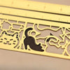 Marcador de metal con regla, diseño de silueta de un gato sobre fondo de madera clara.