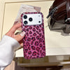 A close-up of a phone case with a leopard print design and pink sequins is held by a hand next to a brown leather bag.