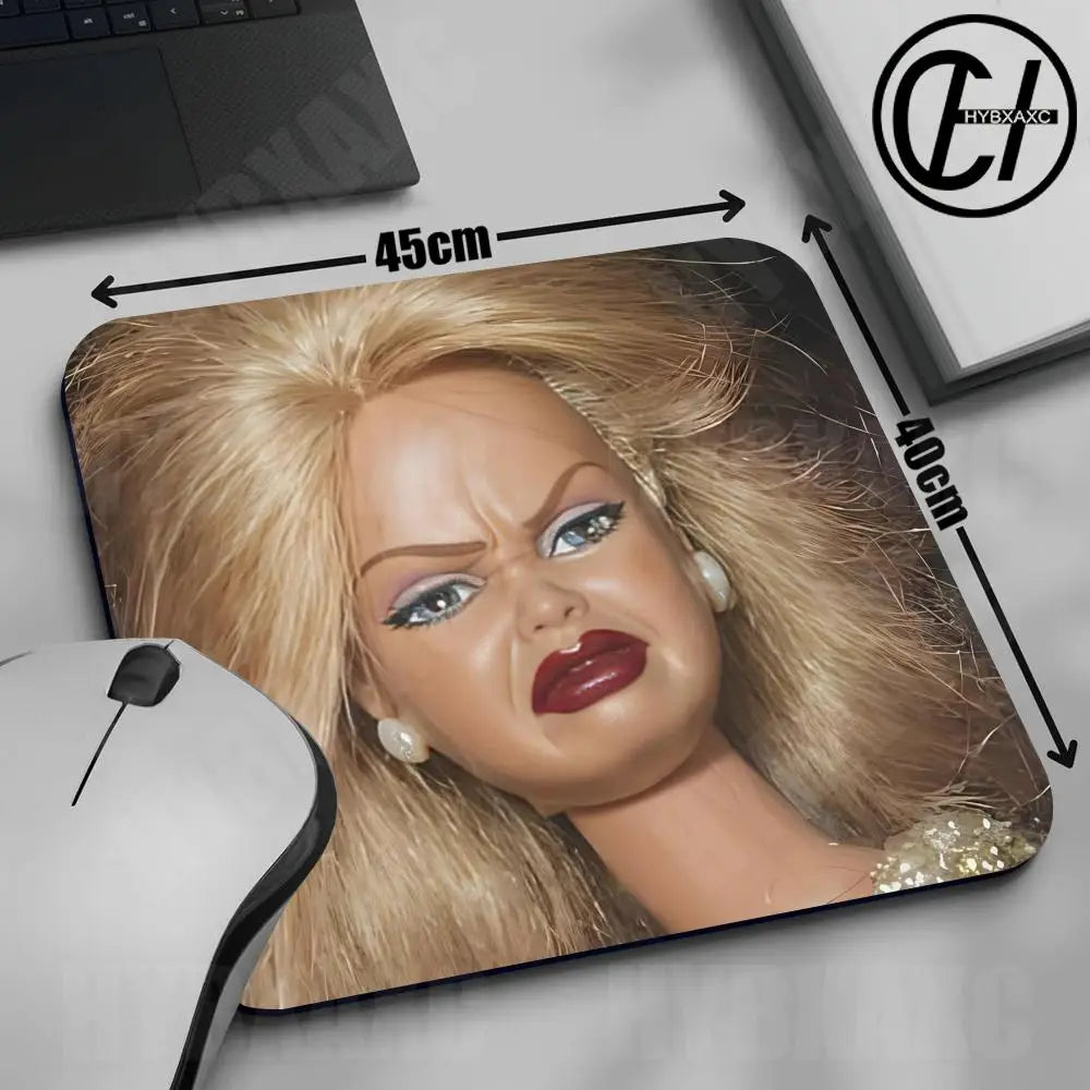 A realistic doll face mouse pad featuring blonde hair and makeup, shown next to a computer mouse.