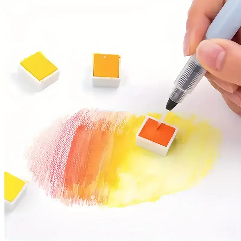 Una mano sumerge una punta de pincel de acuarela en una paleta de pintura para uso artístico.