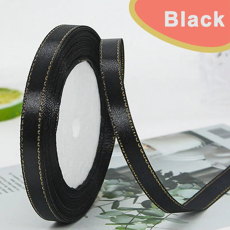 Black satin ribbon rolled on and unrolled, showing a gold edge detail.