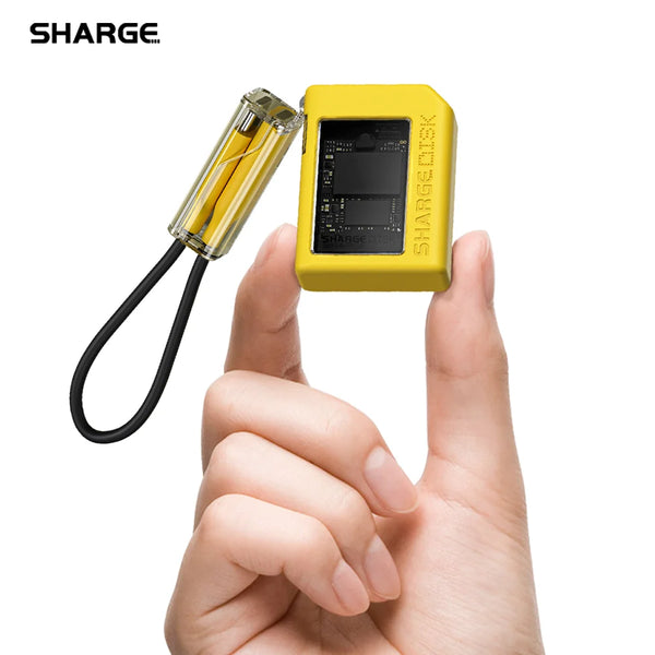 A hand holds a yellow SHARGE M.2 NVMe SSD enclosure device, showing its compact form and connection cable.