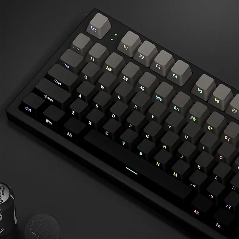 A close-up view of a black mechanical keyboard with gradient gray double shot PBT keycaps and side printing.