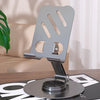 A silver 360-degree rotating mobile phone holder mounted on a stand, shown in a home setting.