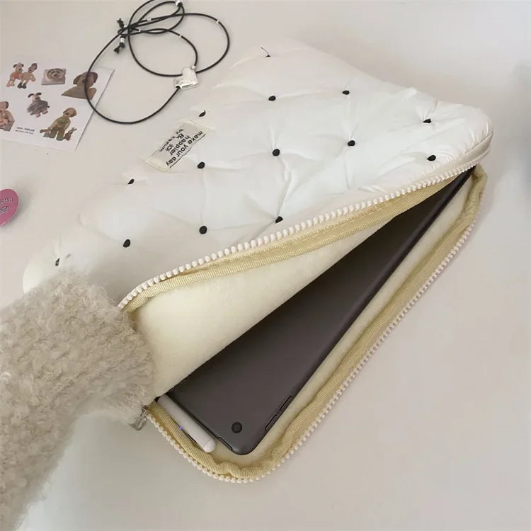 A white quilted padded laptop sleeve case with a light beige lining and a fuzzy gray sleeve visible.