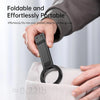 A hand is holding a black magnetic phone tripod stand with a carabiner attached, demonstrating its portable design.