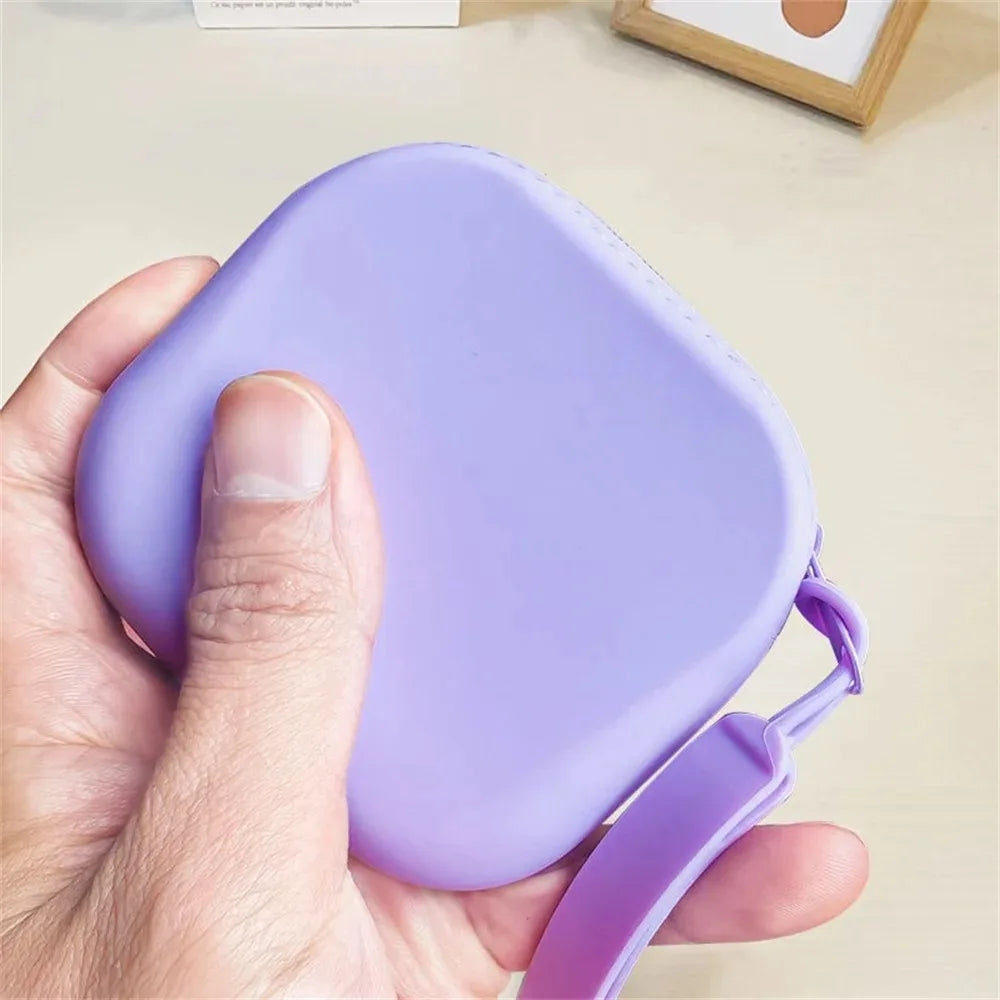 Eine Hand hält eine lila Silikon-Kosmetiktasche mit einem befestigten Armband.