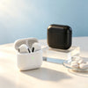 A black charging case and white True Wireless Earbuds with Active Noise Cancellation resting on a light surface.