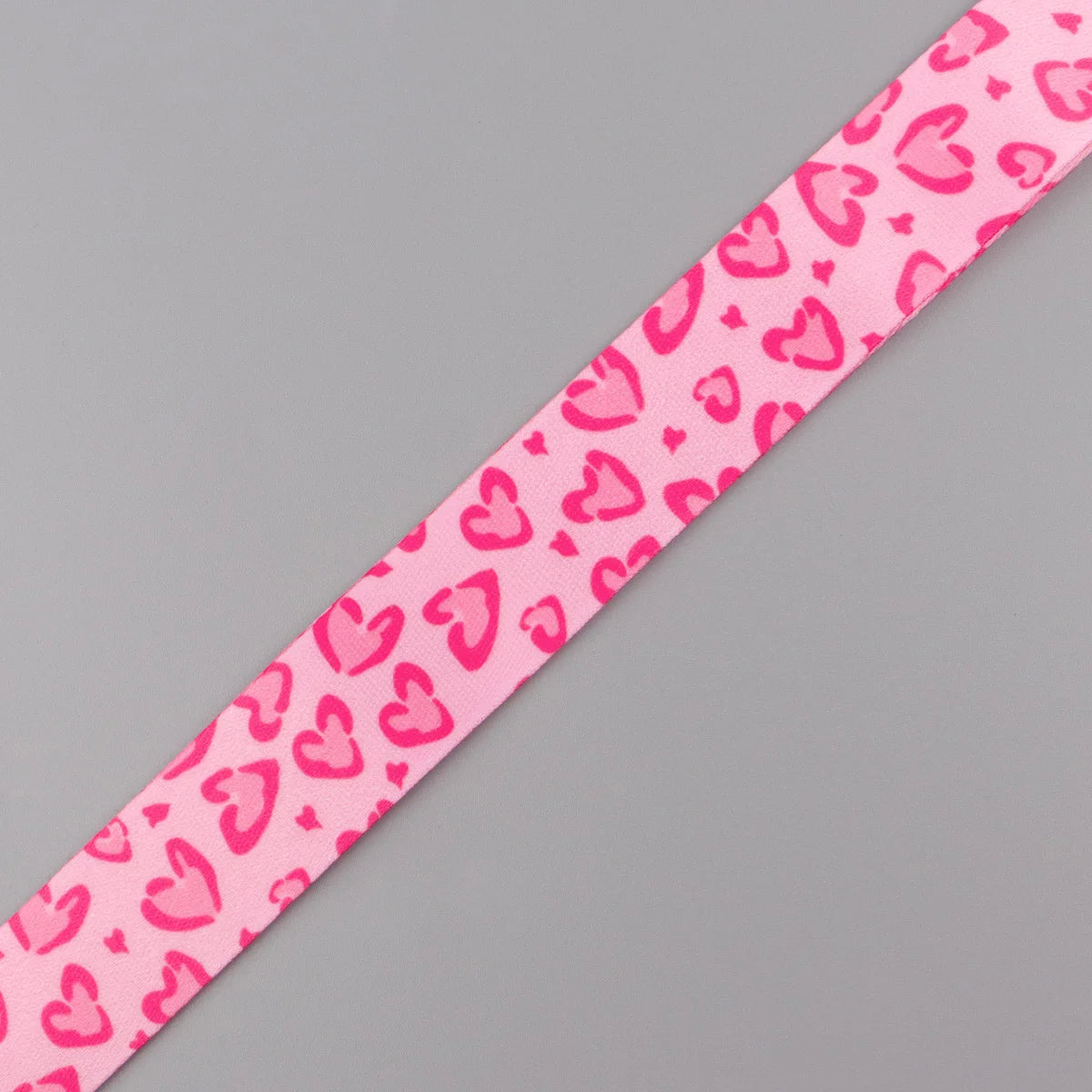 Pink fabric lanyard with a repeating pattern of small pink hearts