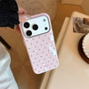 A pink candy polka dot shockproof phone case for an iPhone is being held above a white sink.