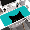 A black cat silhouette is printed on a teal mouse pad placed on a white desk.