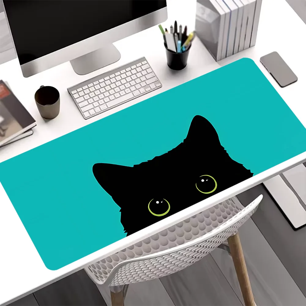 A black cat silhouette is printed on a teal mouse pad placed on a white desk.