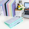 A set of colorful A4 document and photo storage file boxes lined up next to a laptop and a box of flowers.