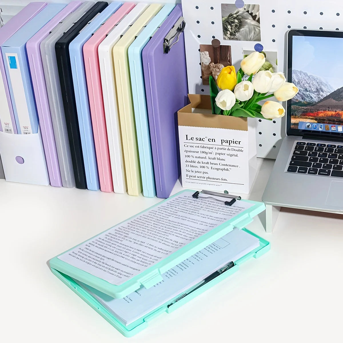 A set of colorful A4 document and photo storage file boxes lined up next to a laptop and a box of flowers.