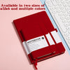 A red hardcover notebook with a white cover and spine is shown next to a white keyboard.