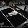 A black gaming mouse pad is displayed on a desk next to a computer monitor and mouse.