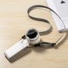 Weißer, faltbarer, wiederaufladbarer USB-Handventilator mit schwarzem Gitter und grauem Riemen auf Holzoberfläche.