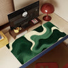 A dark green mouse pad with white abstract wavy patterns is placed on a wooden desk.
