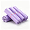 A stack of matte purple self-adhesive mailing bags rolled up and tied with a thin orange ribbon.