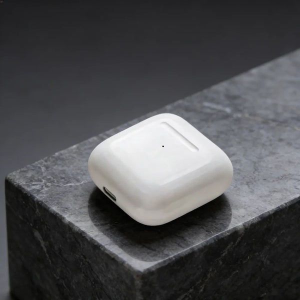 A white mini wireless Bluetooth earphone case resting on a dark gray stone surface.