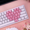 Nahaufnahme einer weißen mechanischen Tastatur mit rosa Schmetterling-Tasten auf einer hellrosa Oberfläche.
