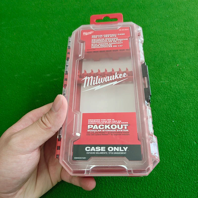 A hand holds a pink plastic storage case for Milwaukee impact driver accessories.