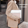 Person in beige blazer holding a white laptop with a mini wireless Bluetooth keyboard and mouse combo.