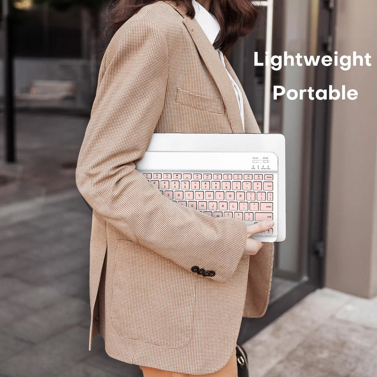 Person in beige blazer holding a white laptop with a mini wireless Bluetooth keyboard and mouse combo.