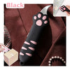 A black cat paw shaped utility knife with a pink detail is shown against a dark brown fabric background.