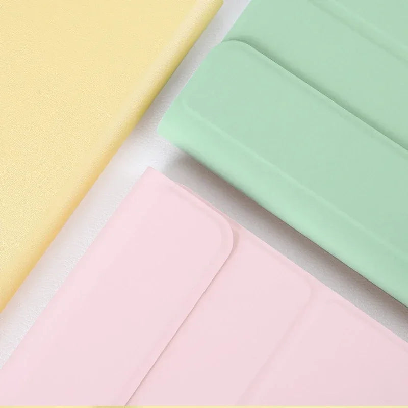 Three colored universal keyboard cases for an iPad, showing yellow, mint green, and pink options.