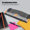 Herramienta de corte para scrapbooking negra con riel deslizante y cuadrículas, junto a un cuaderno y papel de colores.