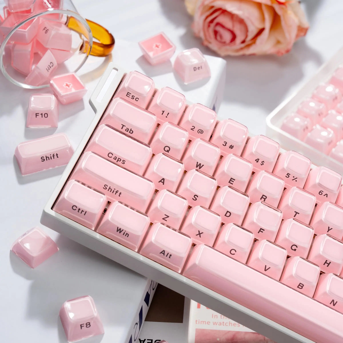 A close-up of a pink mechanical keyboard featuring translucent ice crystal keycaps and surrounding pink accessories.