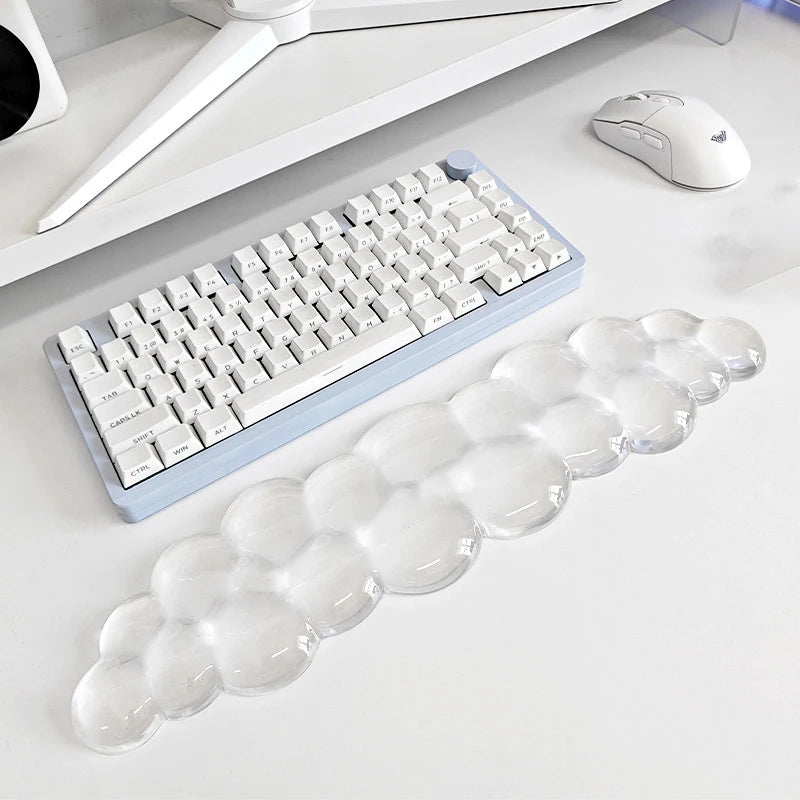 A light blue ergonomic cloud wrist rest for keyboard and mouse placed on a white desk next to a computer mouse.