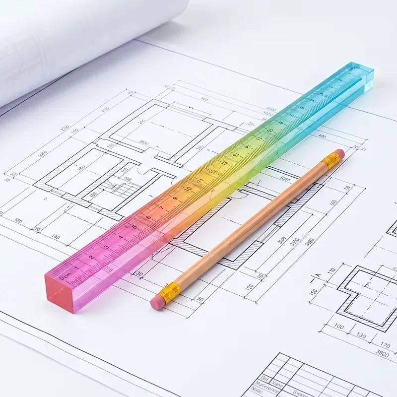 A colorful straight-edge geometric drawing cube is shown next to technical blueprints and rulers.