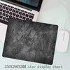 A black gray overlocked mouse pad is shown next to a laptop keyboard.