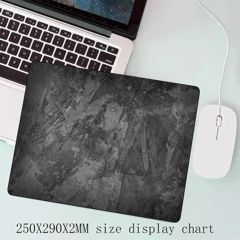 A black gray overlocked mouse pad is shown next to a laptop keyboard.