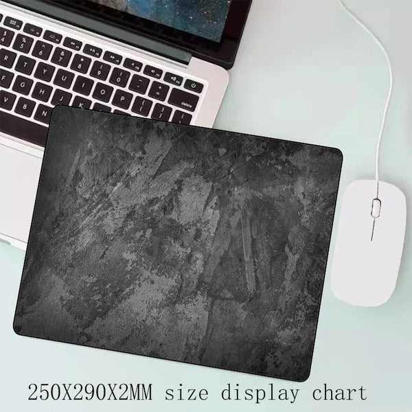 A black gray overlocked mouse pad is shown next to a laptop keyboard.