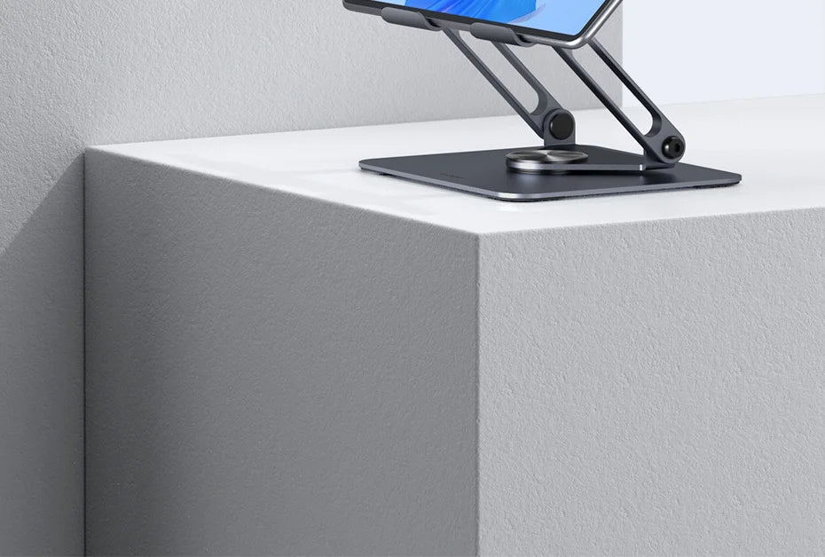 A silver tablet is displayed on a black rotating aluminum stand on a white surface.
